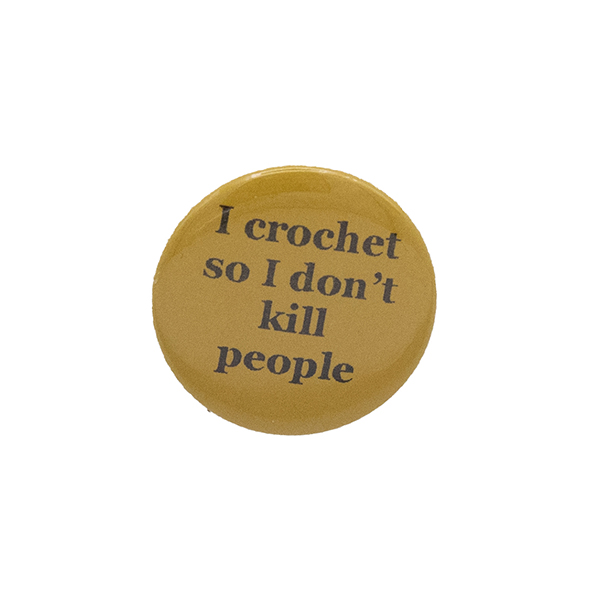 Yellow button badge with black writing which reads I crochet so I don't kill people