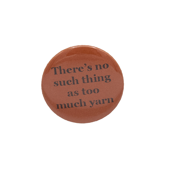 Orange button badge with black writing which reads There's no such thing as too much yarn