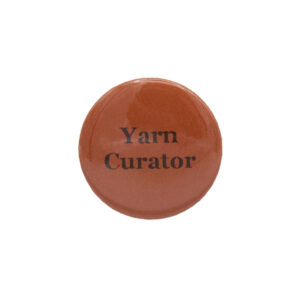 Orange button badge with black writing which reads Yarn Curator