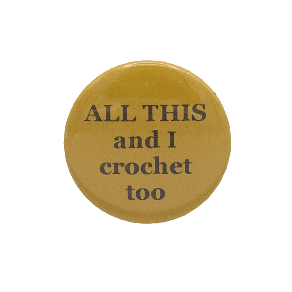Yellow button badge with black writing which reads ALL THIS and I crochet too