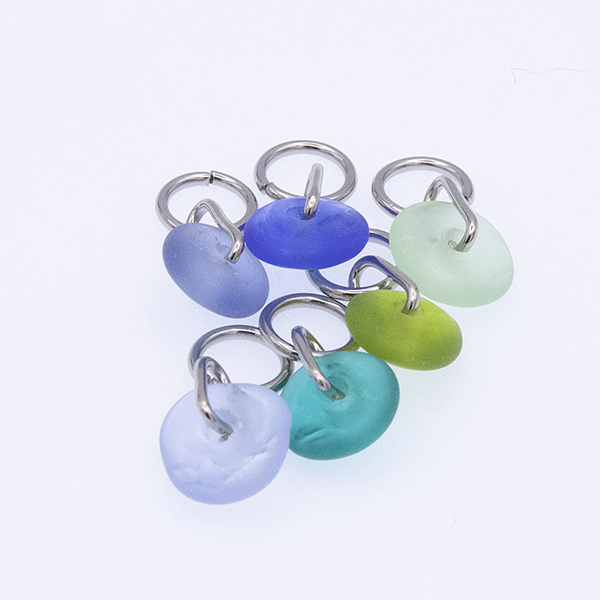six blue and green glass stitch markers in a bundle