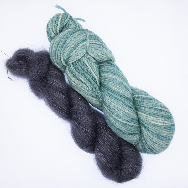 skein of double knit green yarn and smaller skein of dark grey fluffy yarn