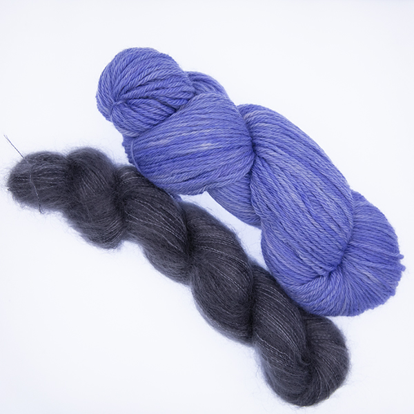 skein of double knit bluish purple yarn and smaller skein of dark grey fluffy yarn