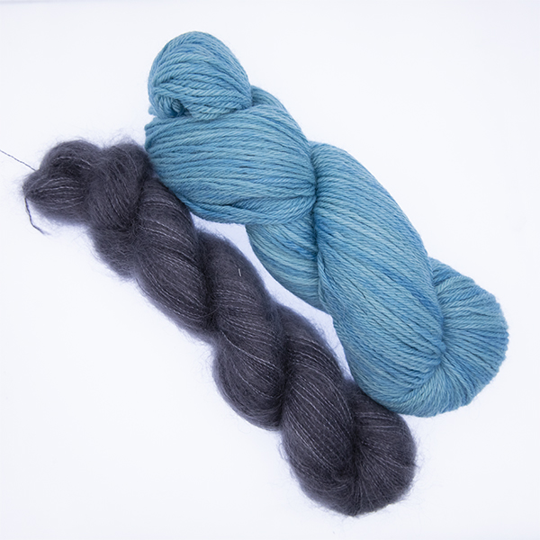 skein of double knit turquoise yarn and smaller skein of dark grey fluffy yarn