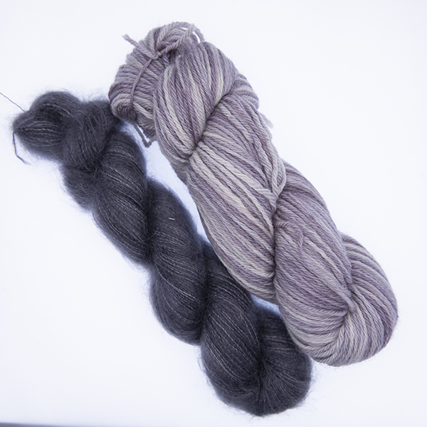 skein of double knit pale grey yarn and smaller skein of dark grey fluffy yarn