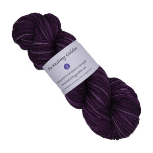skein of darkest raspberry hand dyed yarn with The Knitting Goddess label