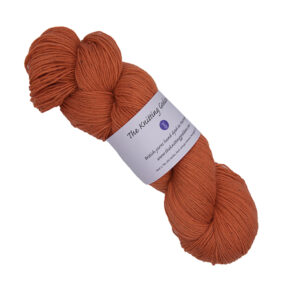 skein of orange hand dyed yarn with The Knitting Goddess label