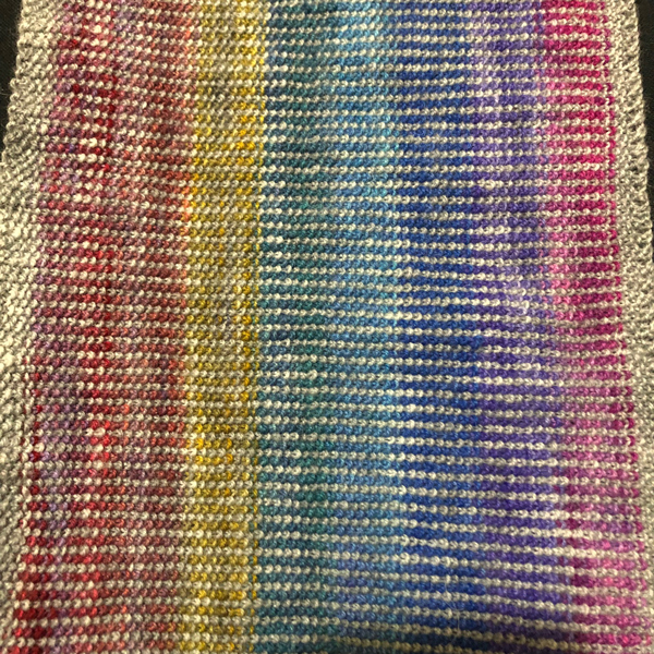 close up of texture of linen stitch cown showing bands of silverstitches and rainbow stripes
