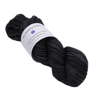 a skein of black hand dyed BFL nylon sock yarn with The Knitting Goddess ball band