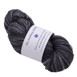 a skein of dark gray charcoal hand dyed BFL nylon sock yarn with The Knitting Goddess ball band