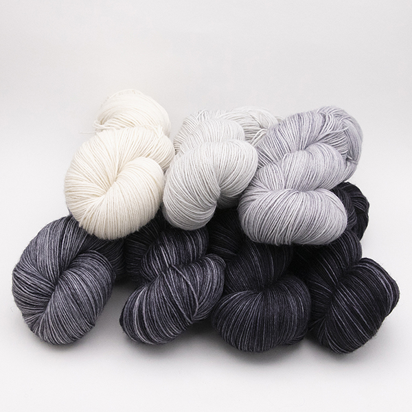 seven skeins of hand dyed yarn ranging from pale cream to almost black