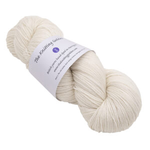 a skein of pale cream hand dyed BFL nylon sock yarn with The Knitting Goddess ball band
