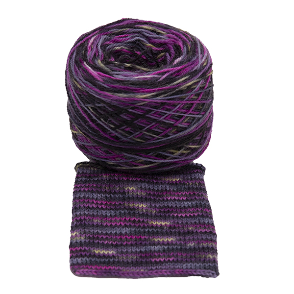 A ball of yarn with a swatch of Hope : the light within the dark Britsock. dark grey background, pink lines and flashes of yellow