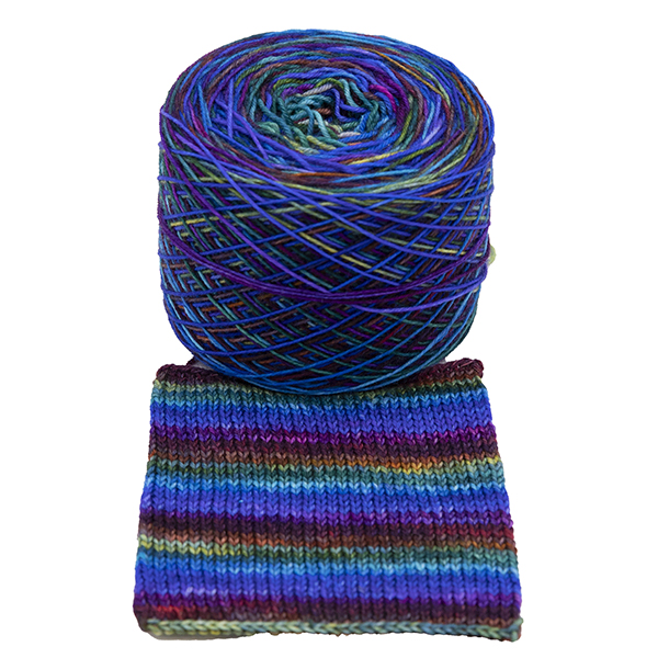 Ball of self striping sock yarn Blue Rainbow . Rainbow colours overdyed with blue giving a tinted rainbow, shown with knitted sample