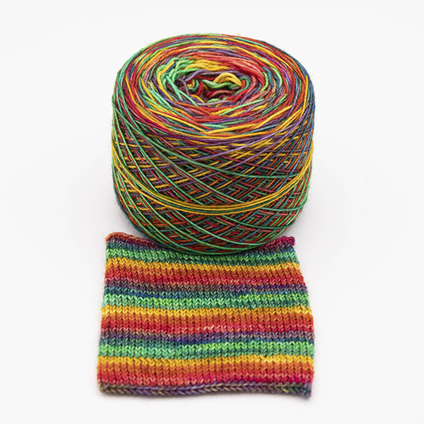 Ball of self striping sock yarn Golden Rainbow . Rainbow colours overdyed with bright gold giving brigth oranges, yellows and limes colours, shown with knitted sample