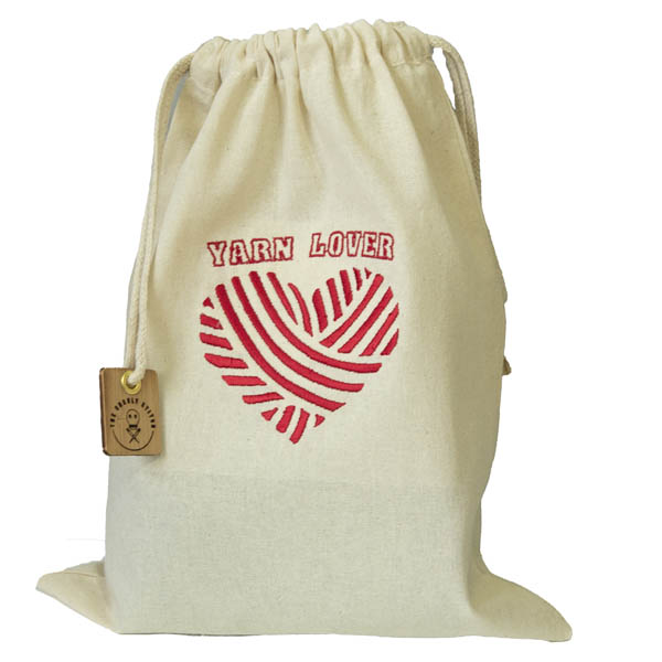 cream drawstring bag embroidered with a heart shaped ball of yarn and the words YARN LOVER. All embroidery is in red.