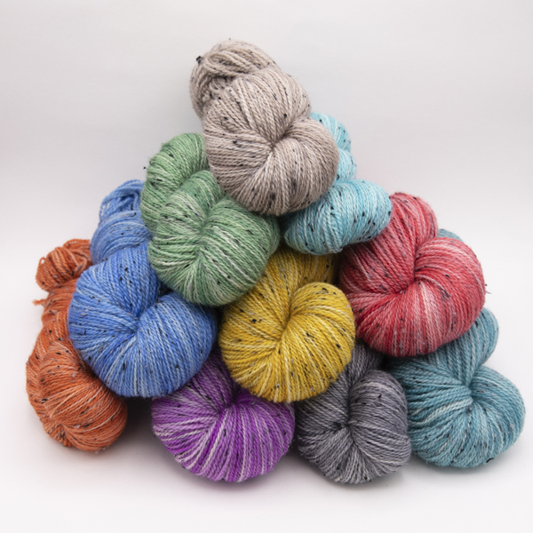 a pyramid f skeins of hand dyed 4ply tweed yarn. Ecah skein is dyed ina  different semi solid colour.