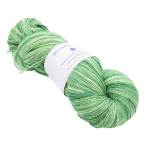 skein of hand dyed pea green sock yarn with The Knitting Goddess ball band