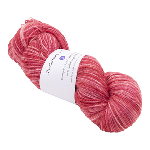 skein of hand dyed red sock yarn with The Knitting Goddess ball band