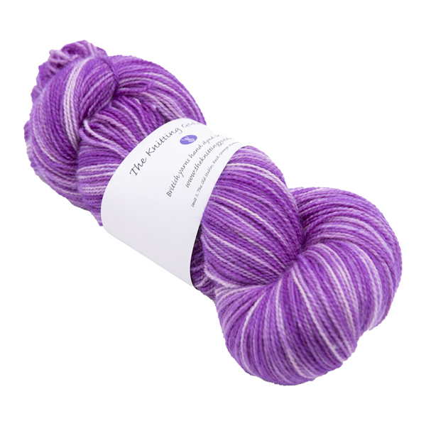 skein of hand dyed pinkish purple sock yarn with The Knitting Goddess ball band