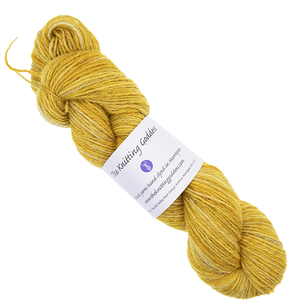 gold skein of hand dyed yarn with The Knitting Goddess ball band