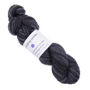 very dark grey skein of hand dyed yarn with The Knitting Goddess ball band