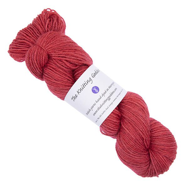 red skein of hand dyed yarn with The Knitting Goddess ball band
