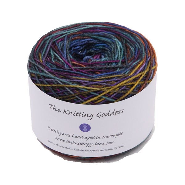 A yarn cake with The Knitting Goddess ball band. Yarn is hand dyed in rainbow colours and overdyed with black.