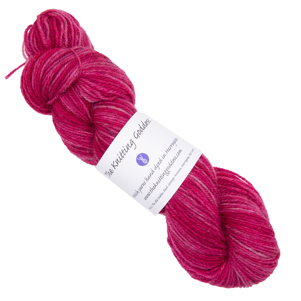 pinkish red skein of hand dyed yarn with The Knitting Goddess ball band