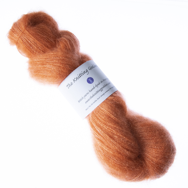Copper hand dyed fluffy mohair silk yarn in a skein with The Knitting Goddess ball band