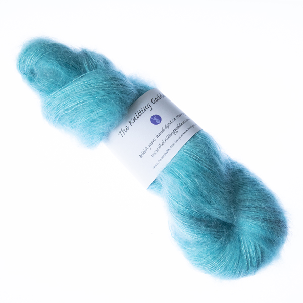 Turquoise hand dyed fluffy mohair silk yarn in a skein with The Knitting Goddess ball band