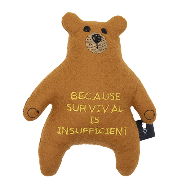 caramel felt bear embroidered with the text "BECAUSE SURVIVAL IS INSUFFICIENT"