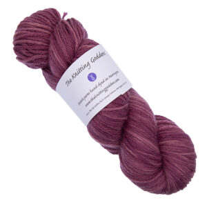 skein of plum hand dyed DK weight wool yarn with The Knitting Goddess ball band