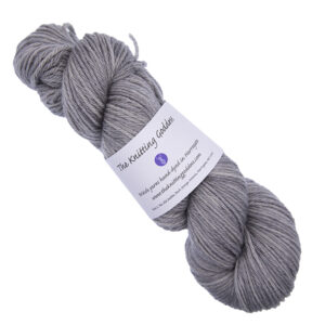 skein of pale silver grey hand dyed DK weight wool yarn with The Knitting Goddess ball band