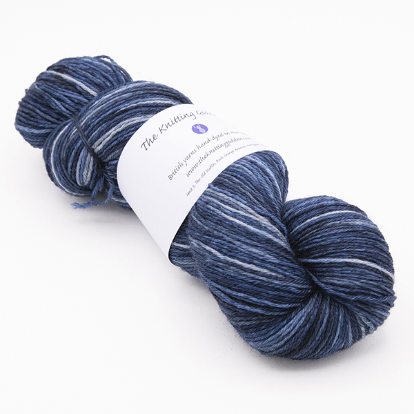 skein of hand dyed blackened blue yarn with The Knitting Goddess label