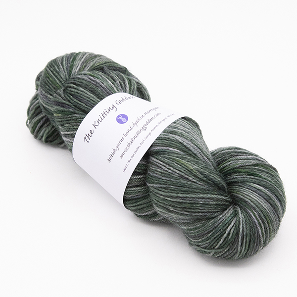 skein of hand dyed blackened forest green yarn with The Knitting Goddess label