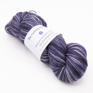 skein of hand dyed blackened purple yarn with The Knitting Goddess label