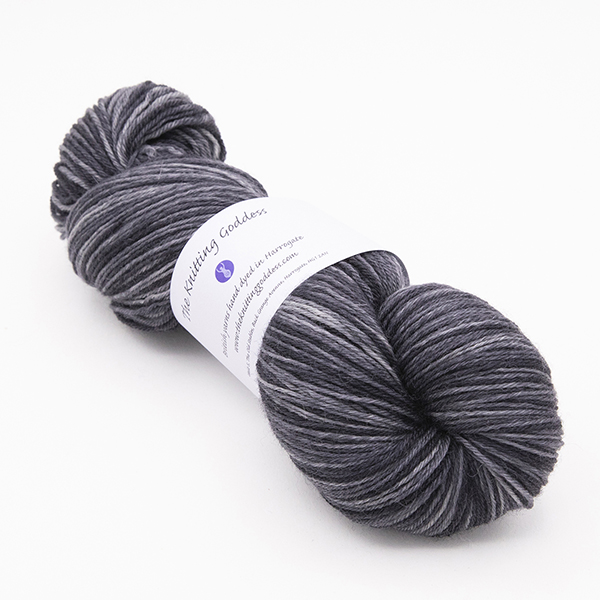 skein of hand dyed charcoal grey yarn with The Knitting Goddess label