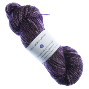 skein of hand dyed plum tweed yarn with The Knitting Goddess label