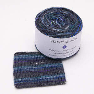 ball and knitted sample of self striping sock yarn with dashes of green, blue, purple and white on black and navy