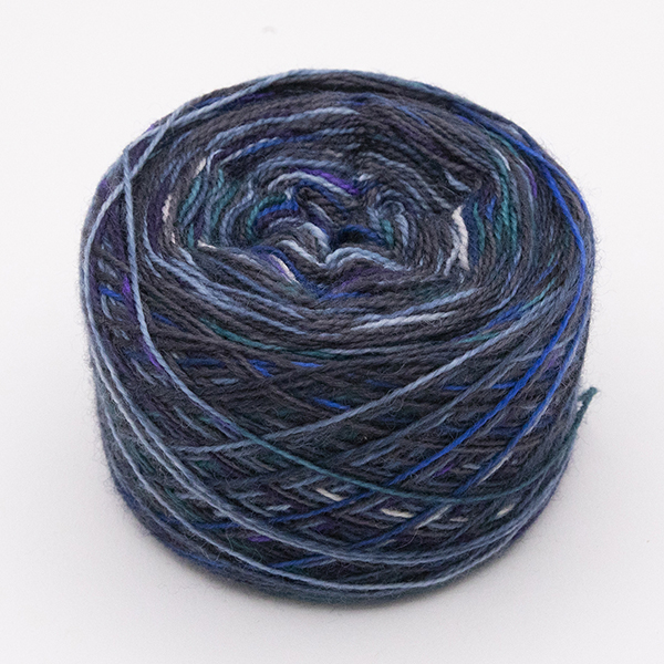 ball of self striping sock yarn with dashes of green, blue, purple and white on black and navy