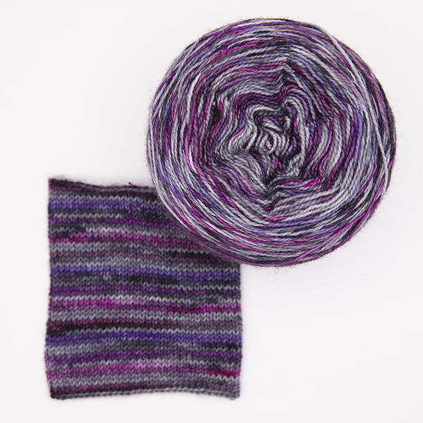 ball and knitted sample of self striping sock yarn with purples, plums and silver top view