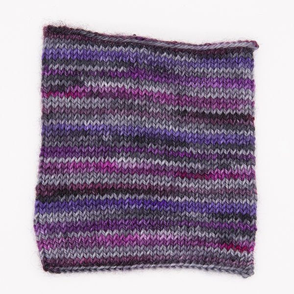 knitted sample of self striping sock yarn with purples, plums and silver