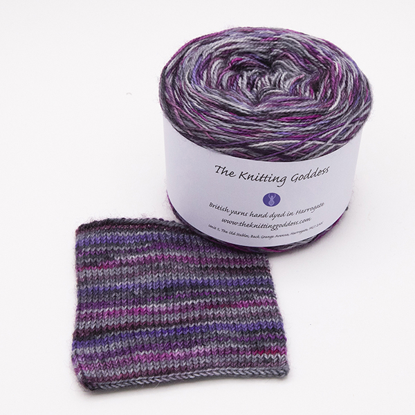 ball and knitted sample of self striping sock yarn with purples, plums and silver