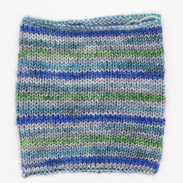 knitted sample of self striping sock yarn with greens, blues and silver