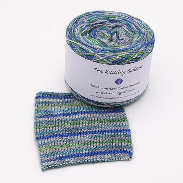 ball and knitted sample of self striping sock yarn with greens, blues and silver