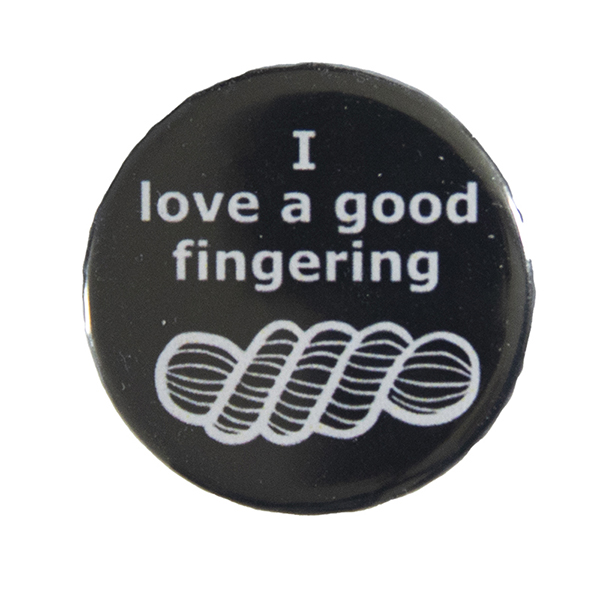black pin badge with text "I love a good fingering" and a line drawing of a skein of yarn