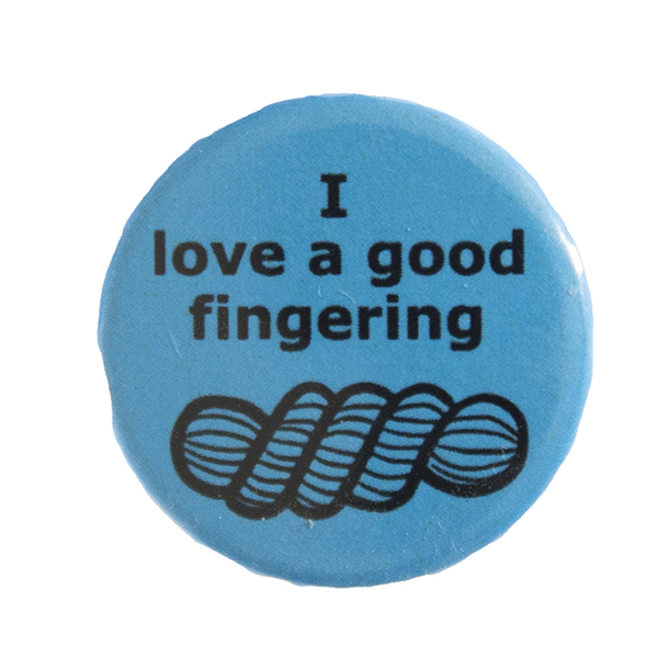 blue pin badge with text "I love a good fingering" and a line drawing of a skein of yarn