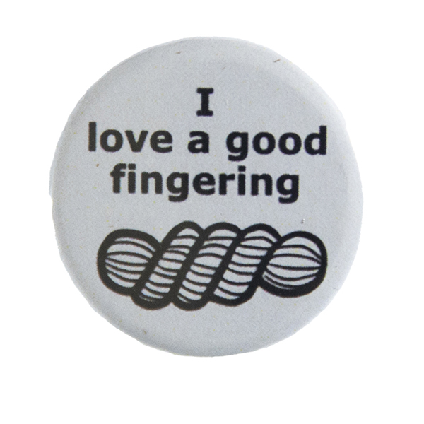 grey pin badge with text "I love a good fingering" and a line drawing of a skein of yarn
