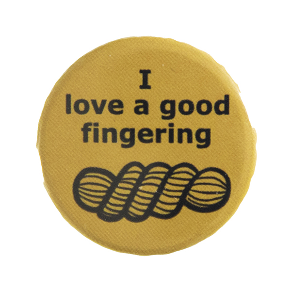 yellow pin badge with text "I love a good fingering" and a line drawing of a skein of yarn